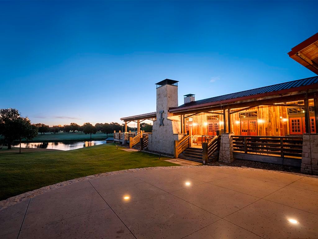 Distillery building lit at twilight beside a pond