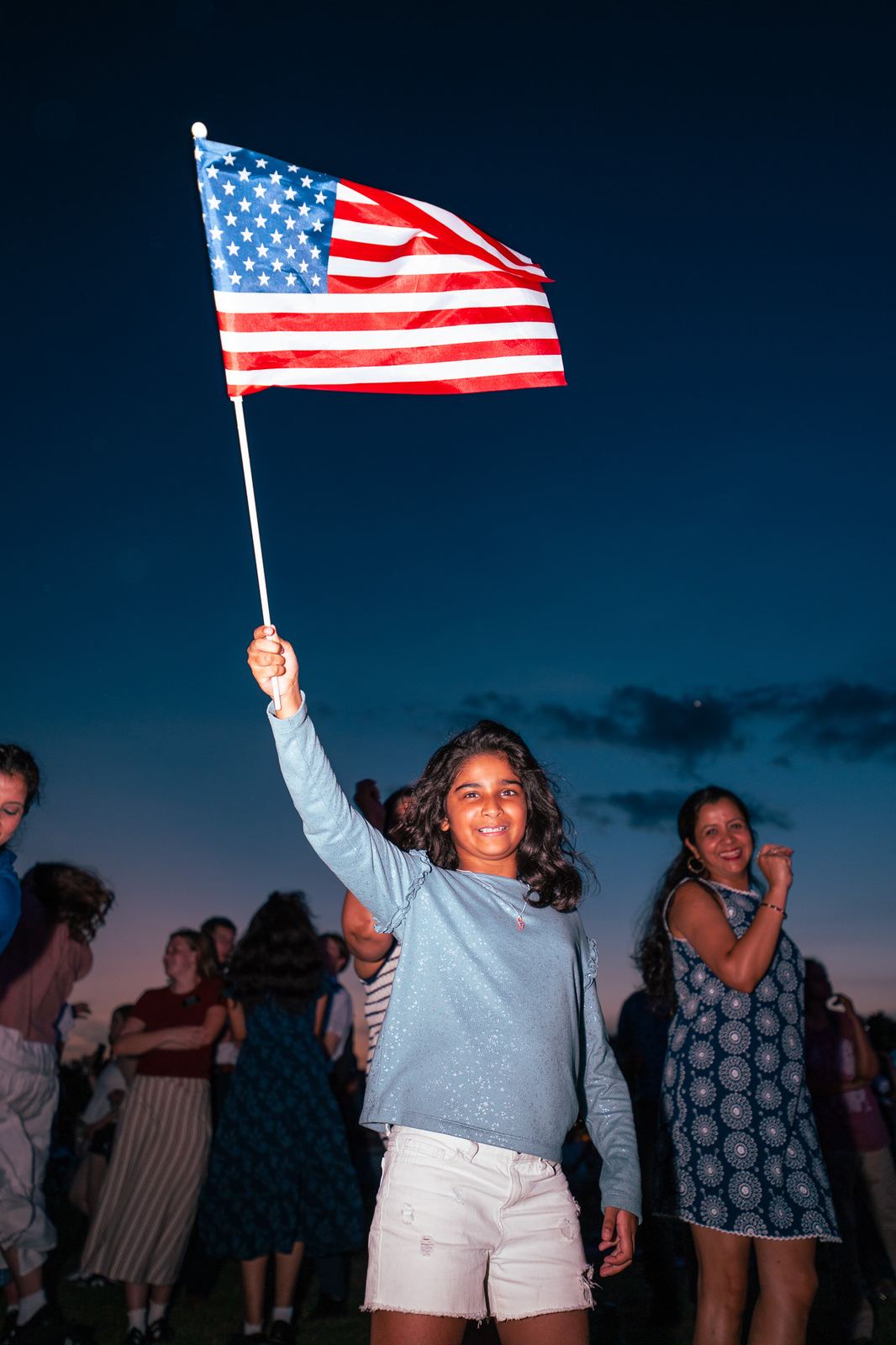 Girl waving an American flag at a Fourth of July celebration