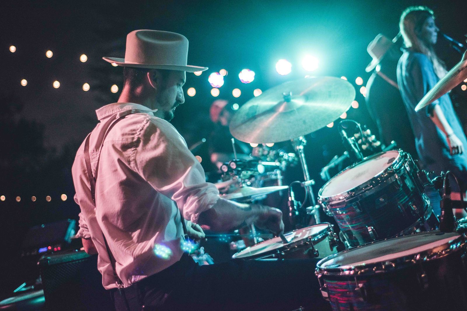 Drummer playing under colored stage lights
