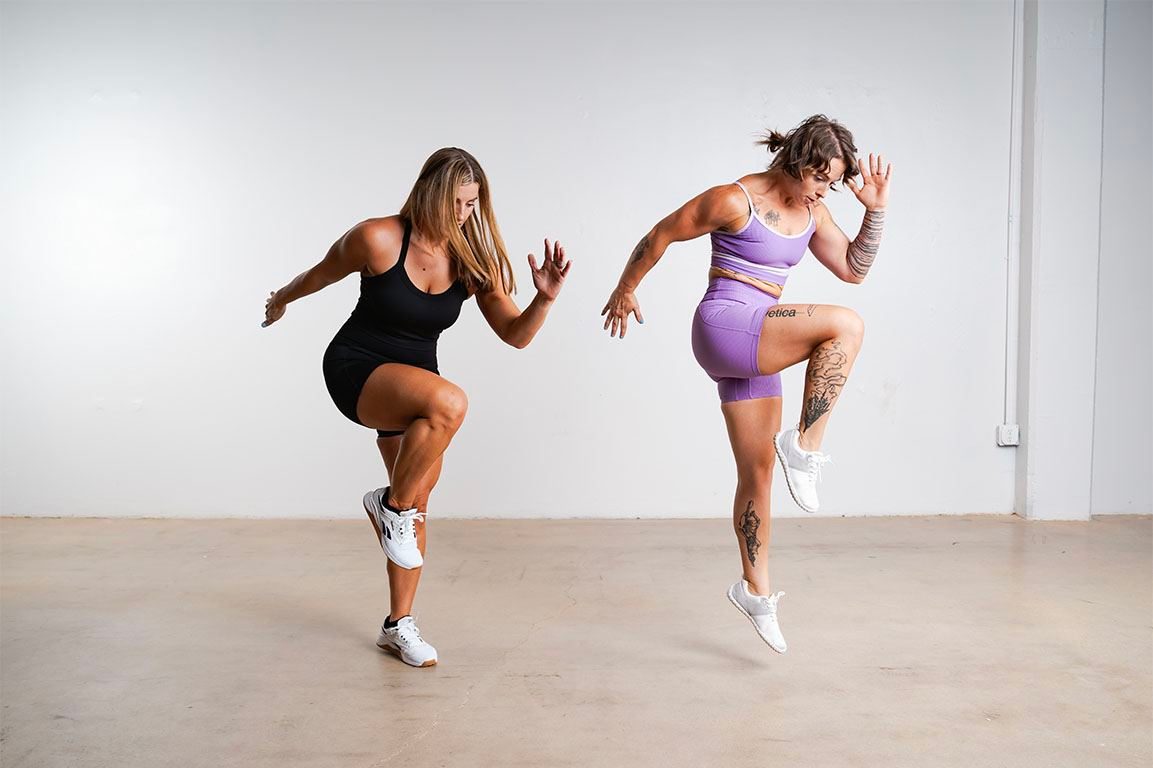 Two athletes jumping in a white studio