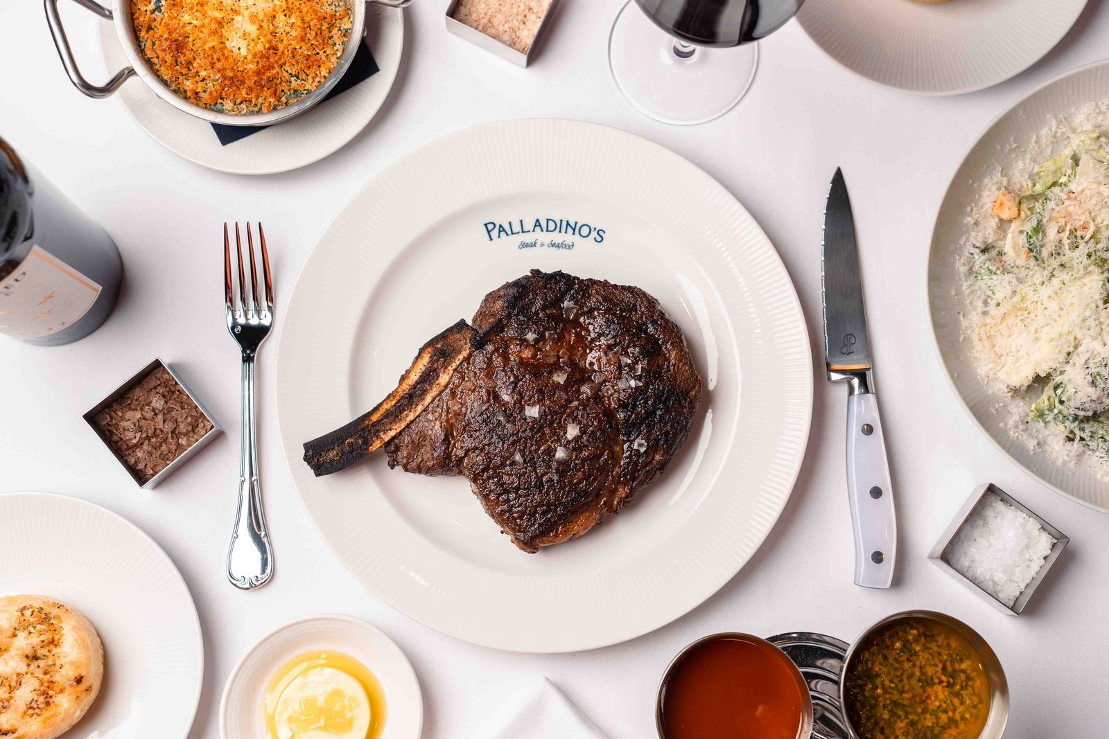 Bone-in steak with sides on a white table
