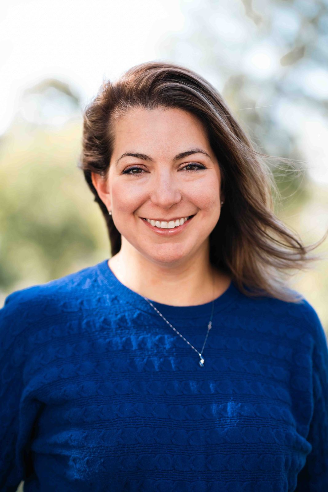 Headshot of a smiling woman in a blue sweater