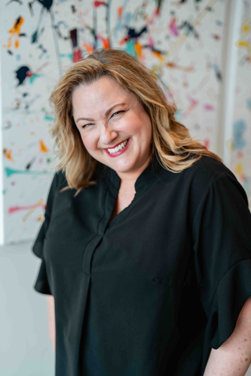 Smiling woman in front of a colorful painted wall