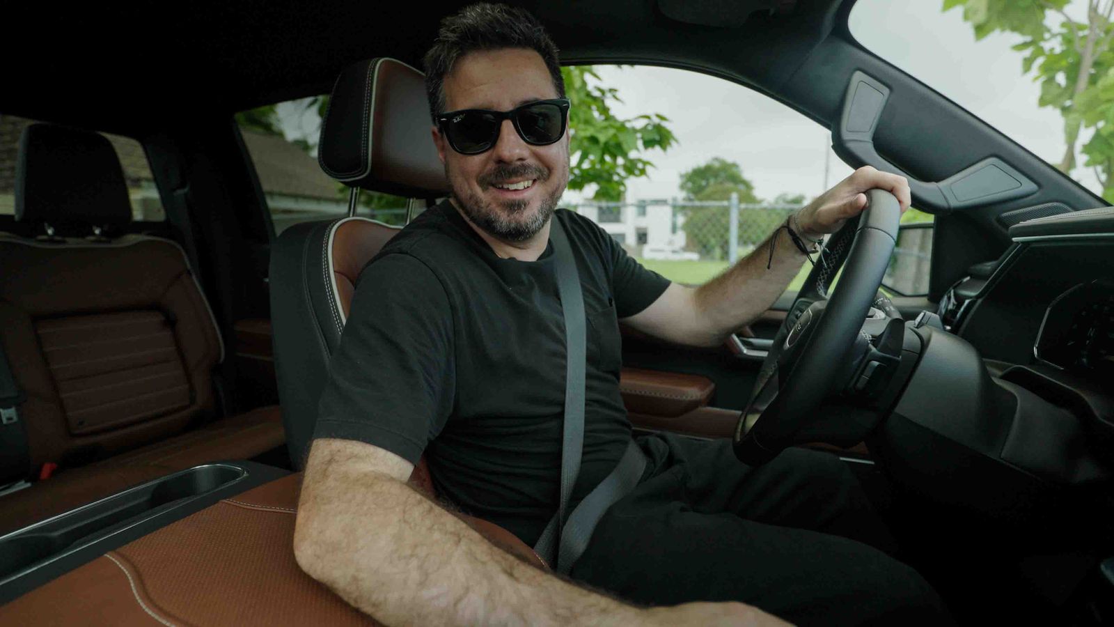 Smiling driver behind the wheel of a GMC Sierra Denali