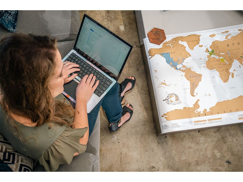 Woman working on a laptop beside a world map