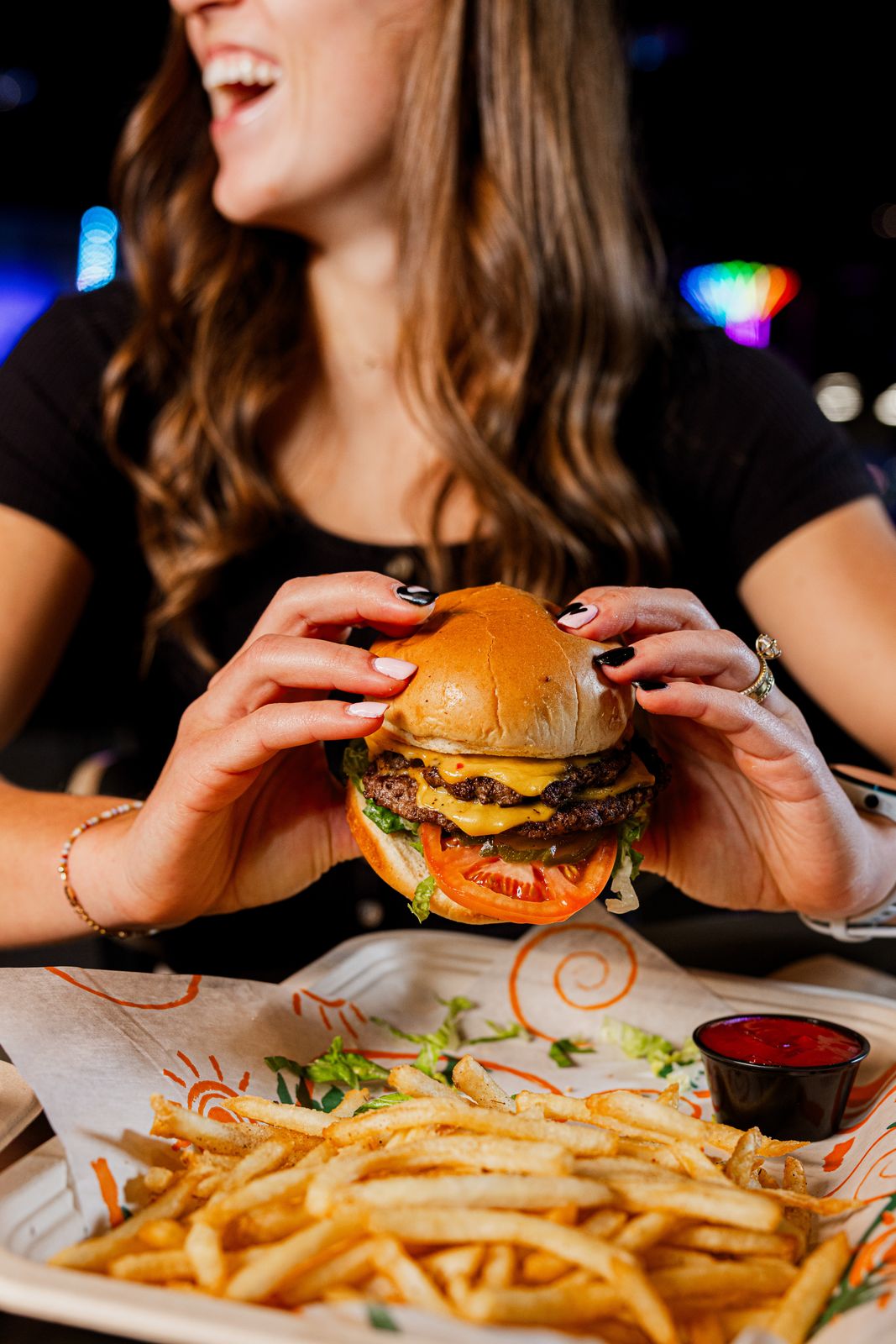 Woman laughing while holding a burger at a restaurant