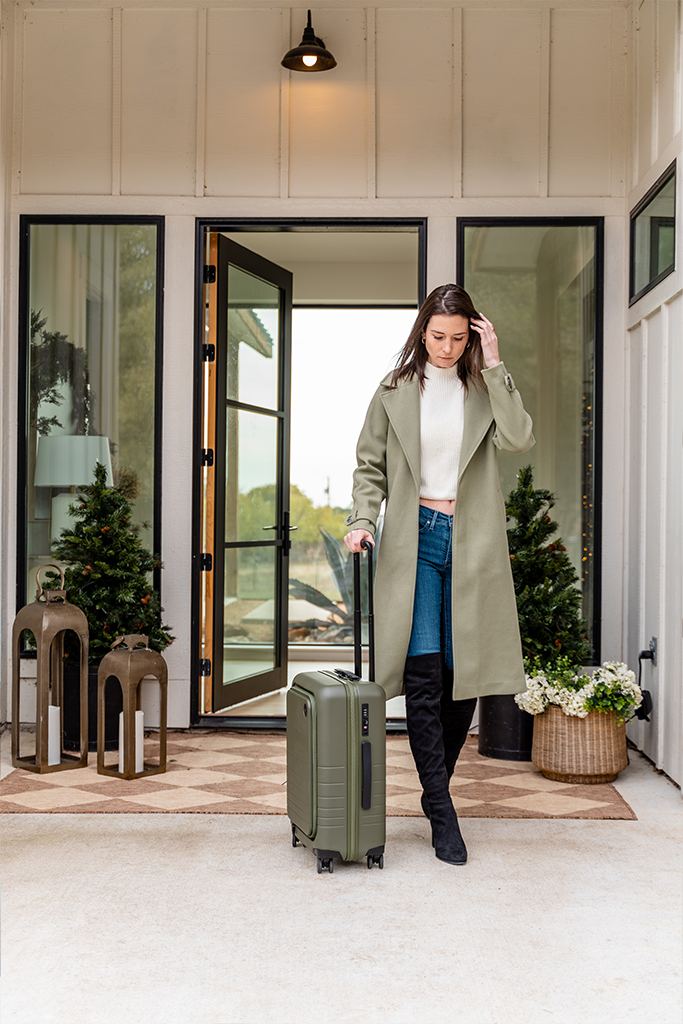 Woman walking out her front door with a suitcase