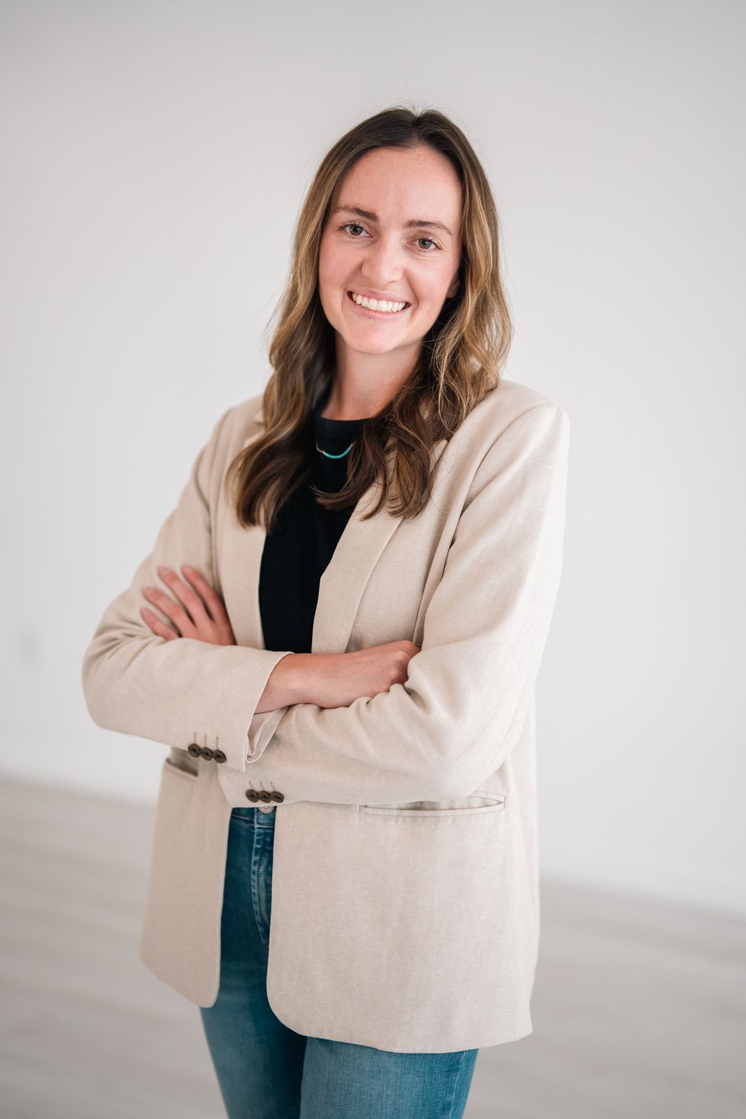 Smiling woman in a cream blazer with arms crossed, personal branding portrait