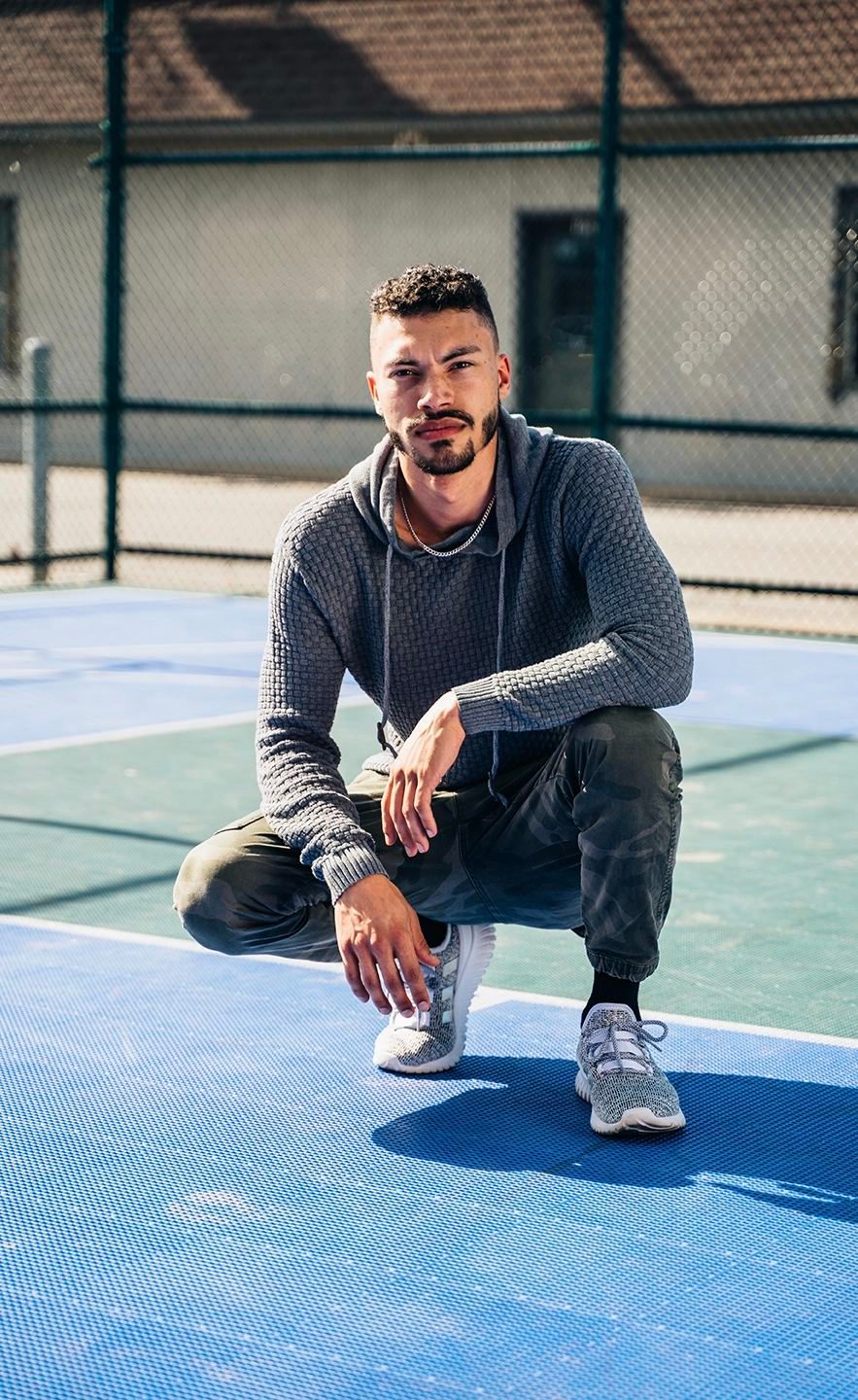 Man crouching on a sport court in a casual portrait