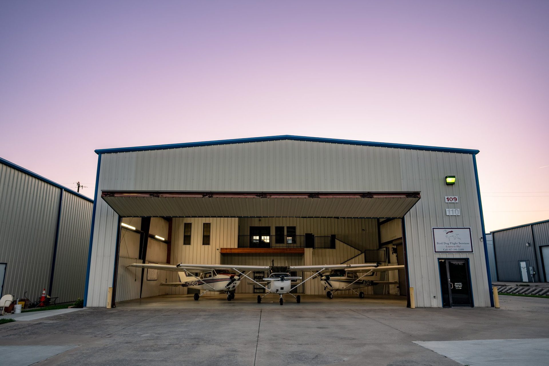 Open hangar with planes inside under a purple dusk sky