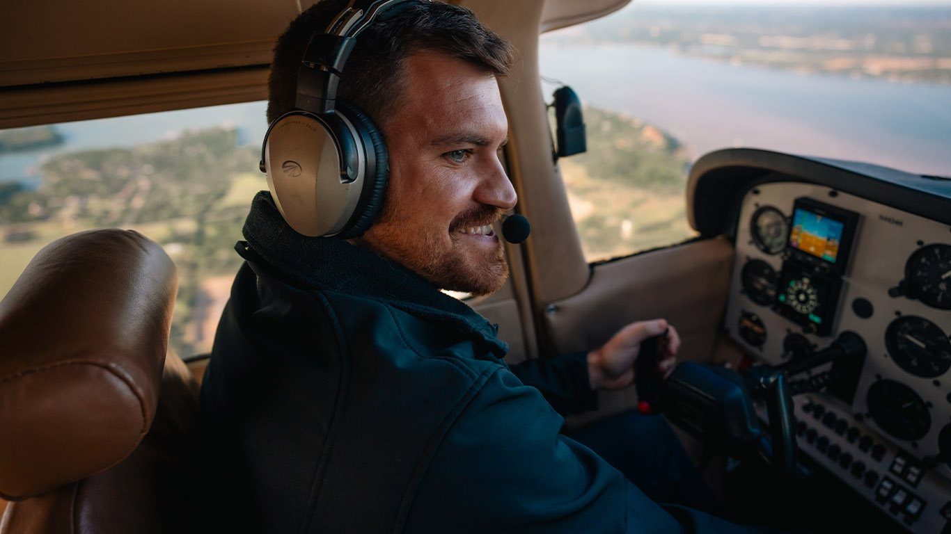 Smiling pilot in a headset at the controls over the lake