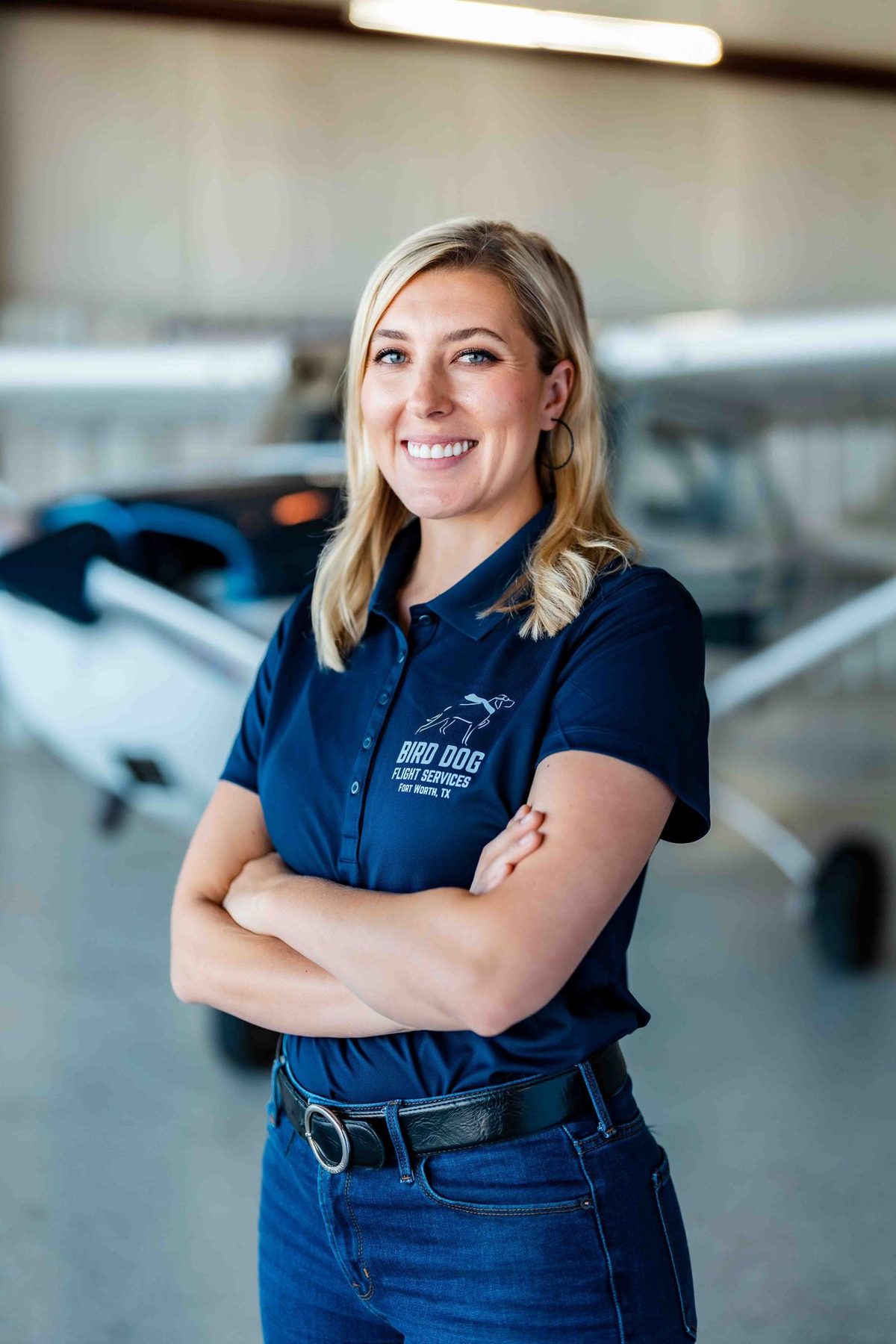 Flight instructor with arms crossed in the hangar in front of a Cessna