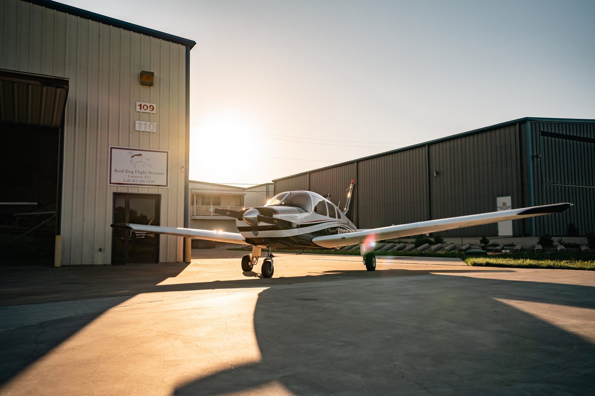 Low-wing plane outside the hangar at sunset