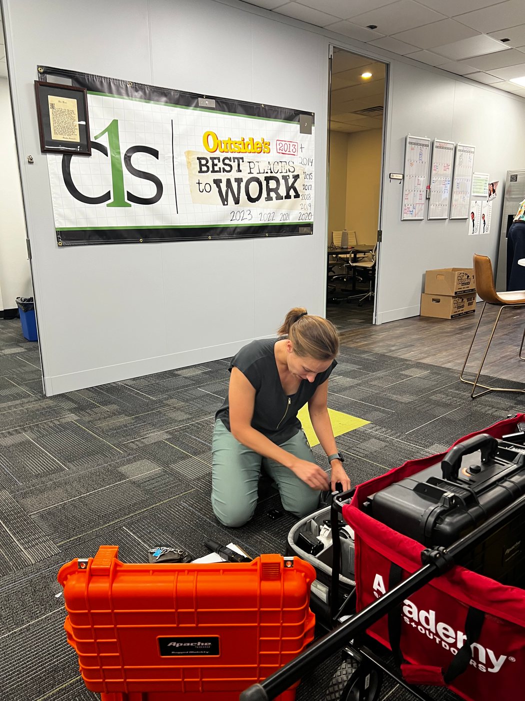 Susie Burleson setting up camera gear under the C1S Best Places to Work banner