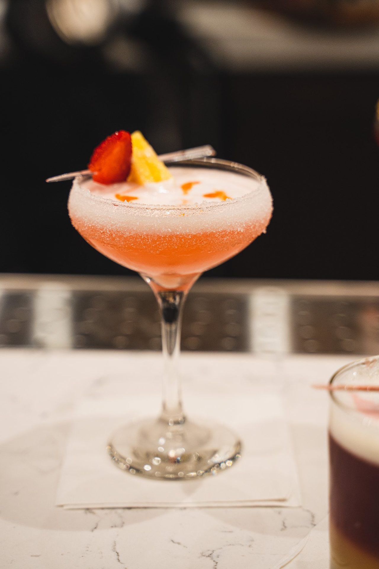 Pink cocktail garnished with strawberry on the bar
