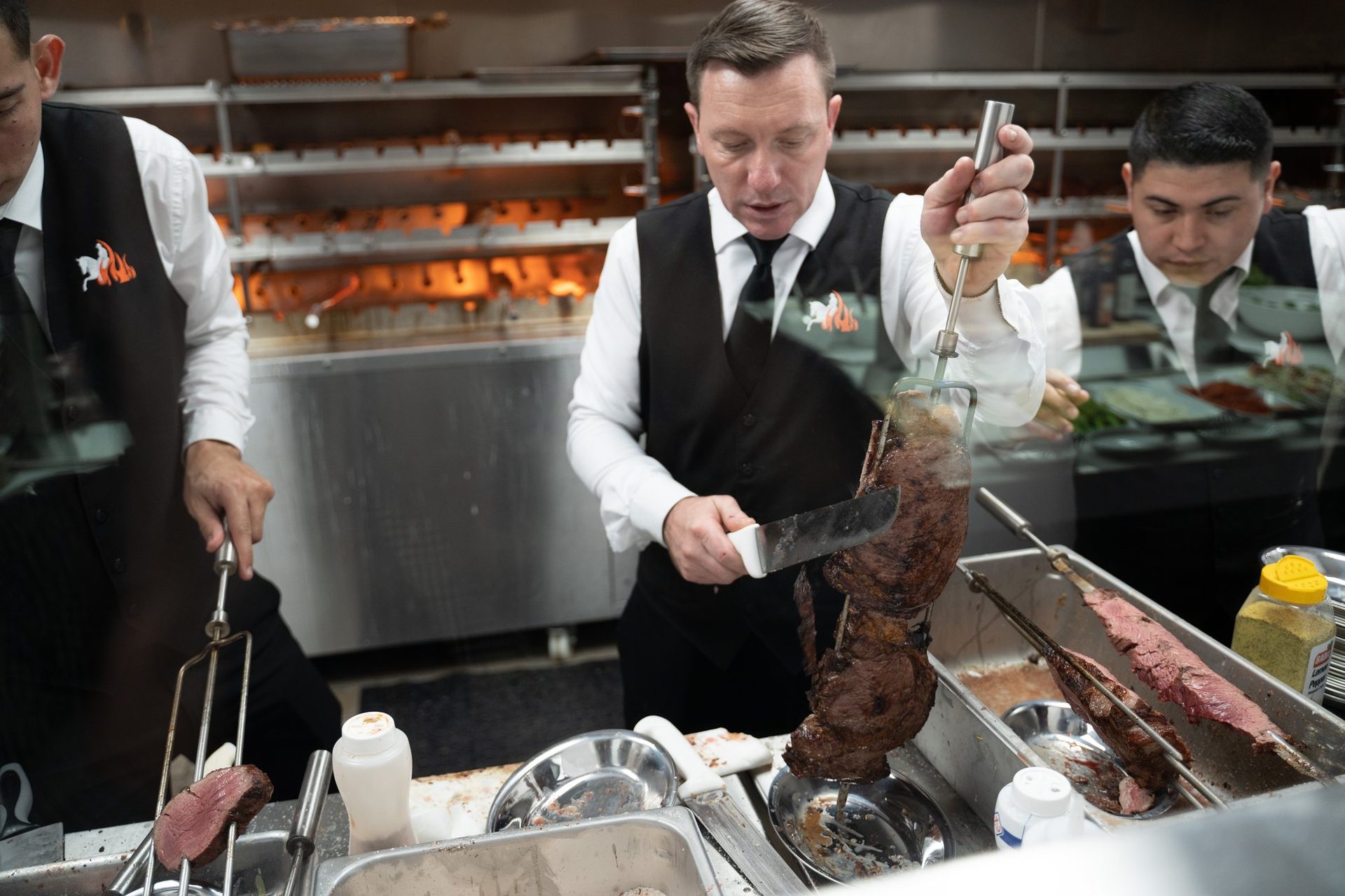 Gaucho carving a skewer at the grill station