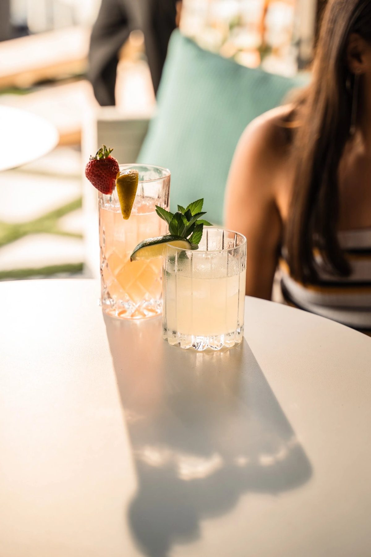 Two gin cocktails on a rooftop table in late sun