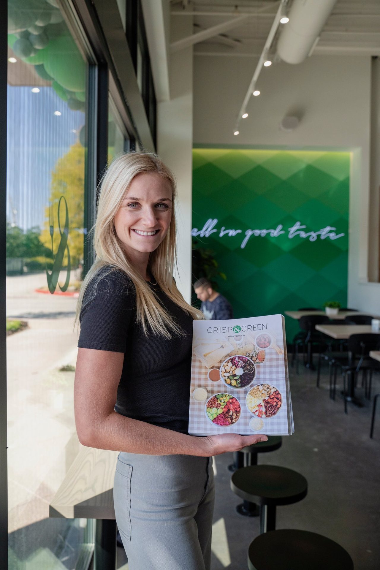 Guest holding a Crisp & Green menu at the opening