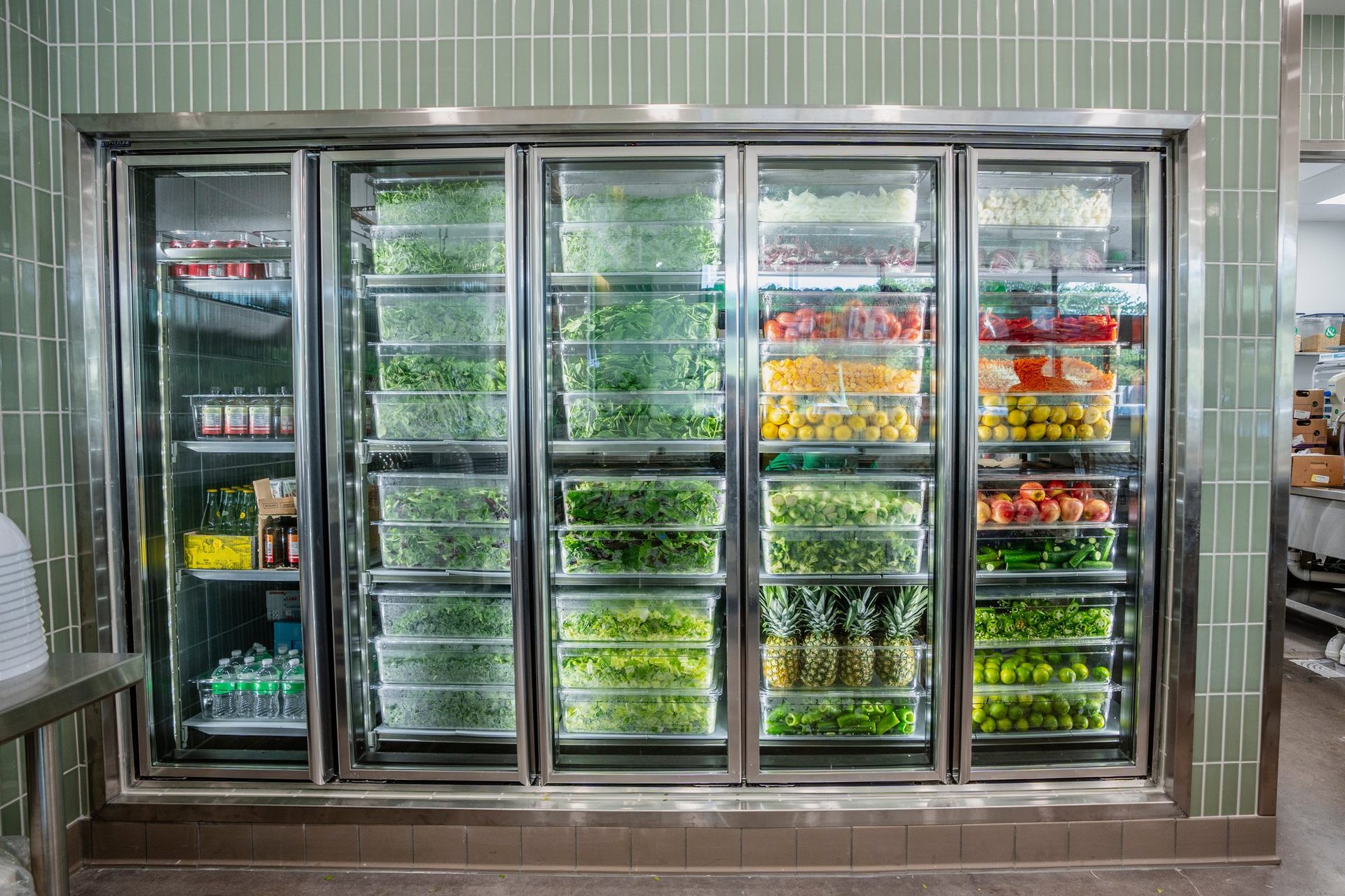 Glass cooler stocked with fresh greens and produce