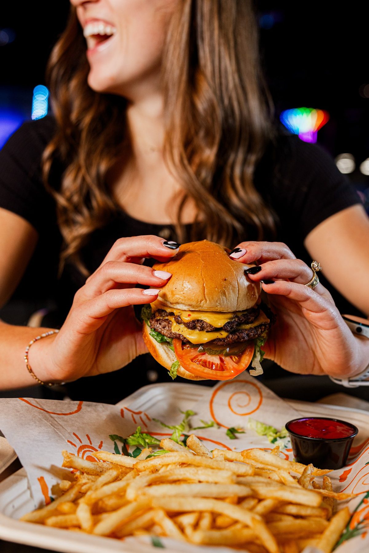 Guest holding a cheeseburger under arcade lights