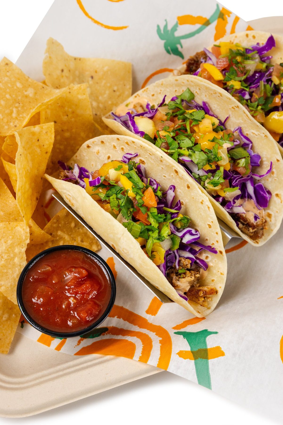 Three tacos with mango salsa and chips, white background