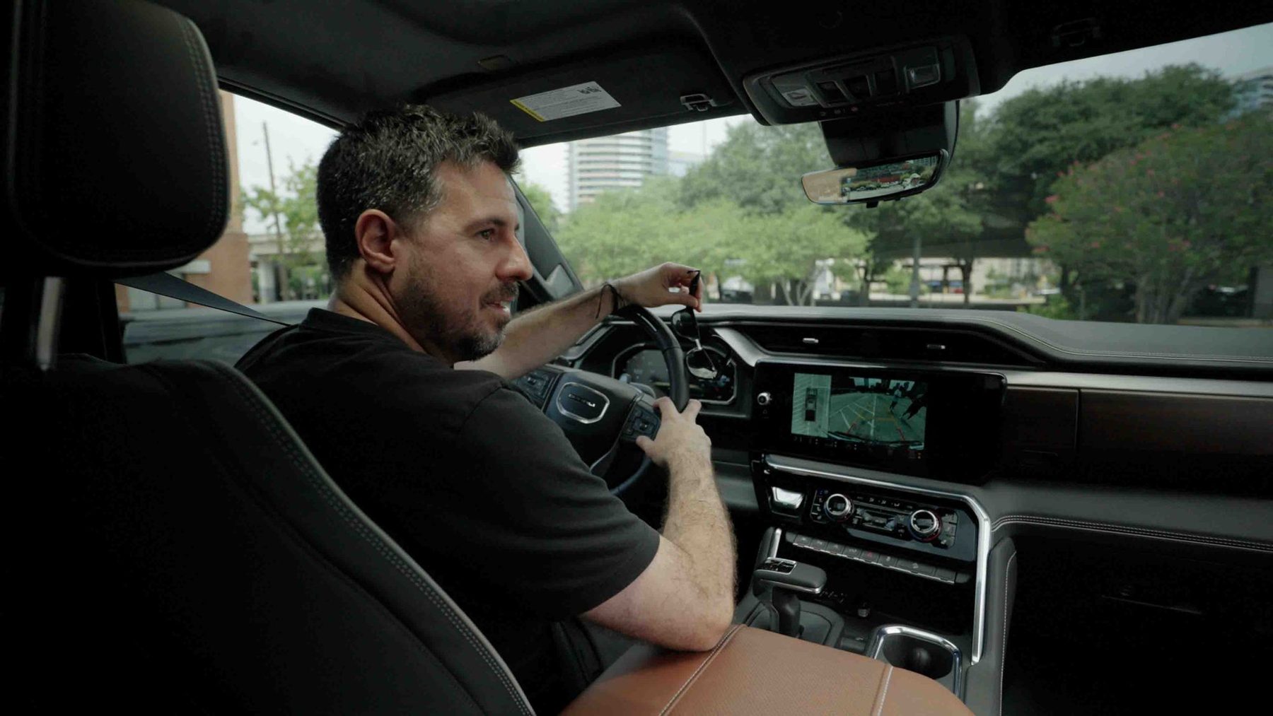 Host smiling behind the wheel of the Sierra Denali