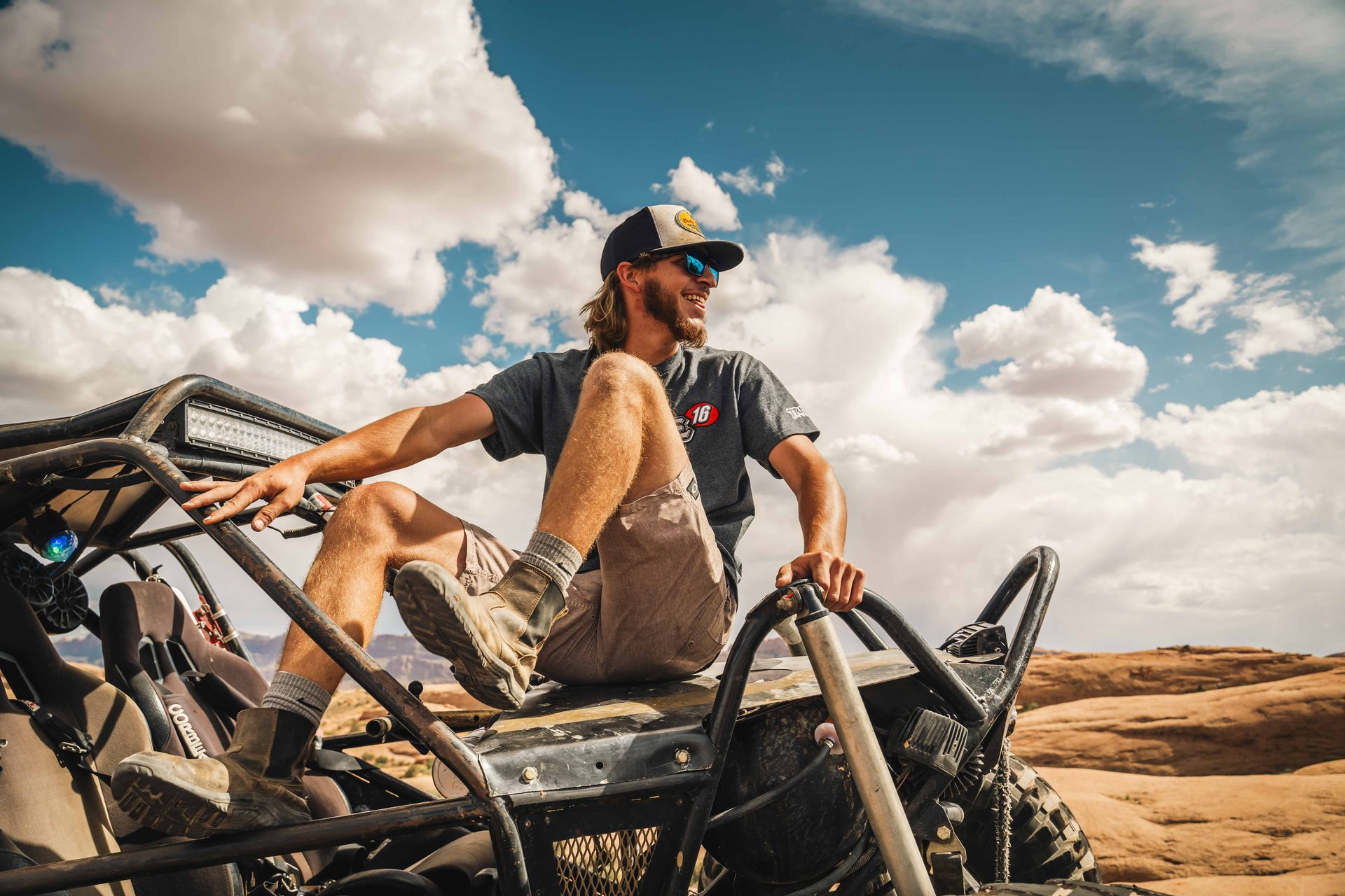Driver standing up in his buggy under big desert clouds