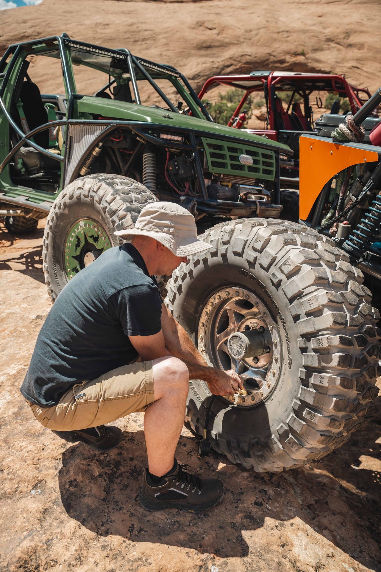 Mechanic working on a tire beside a rock crawler on the trail