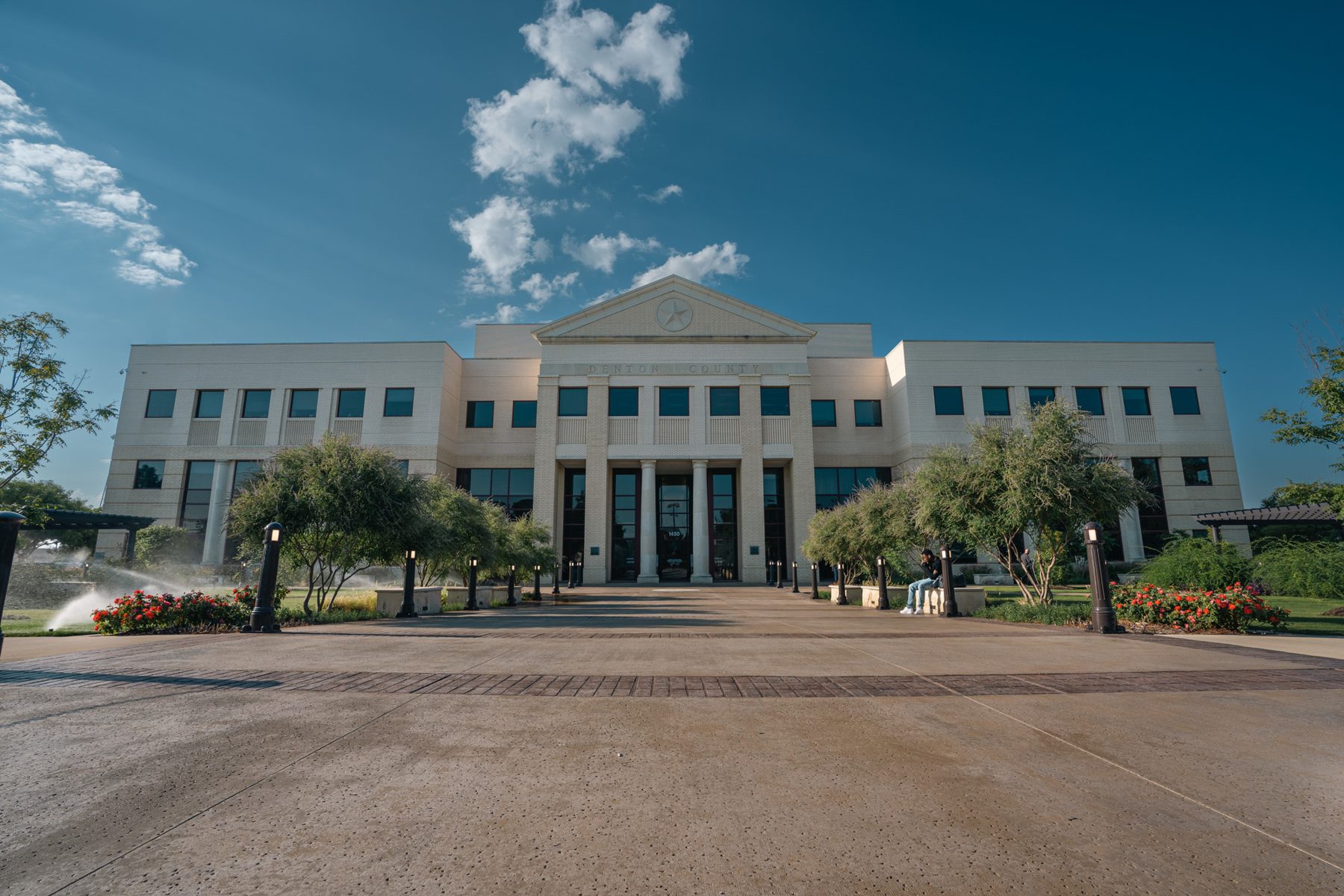 Denton County building and its landscaped entry plaza under a blue sky