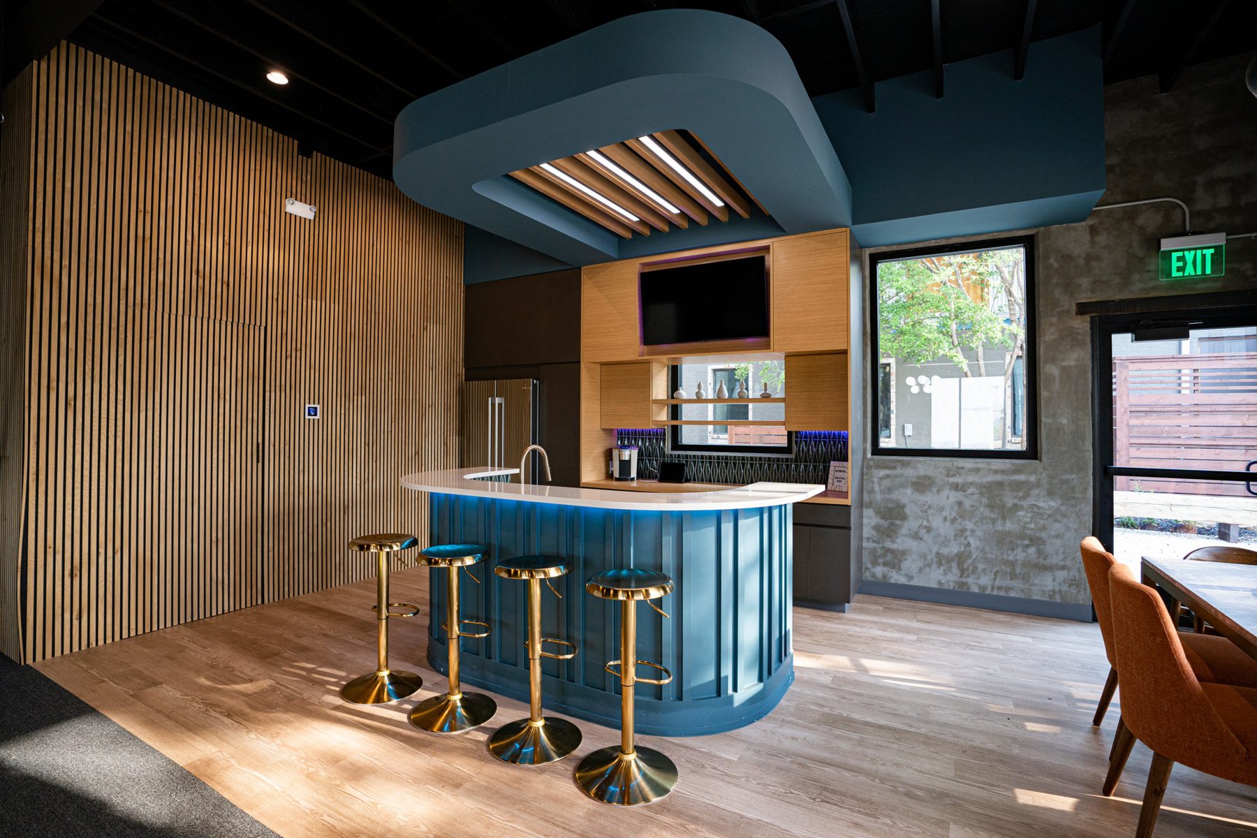 Blue coffee bar with brass stools in the Valley Quest office