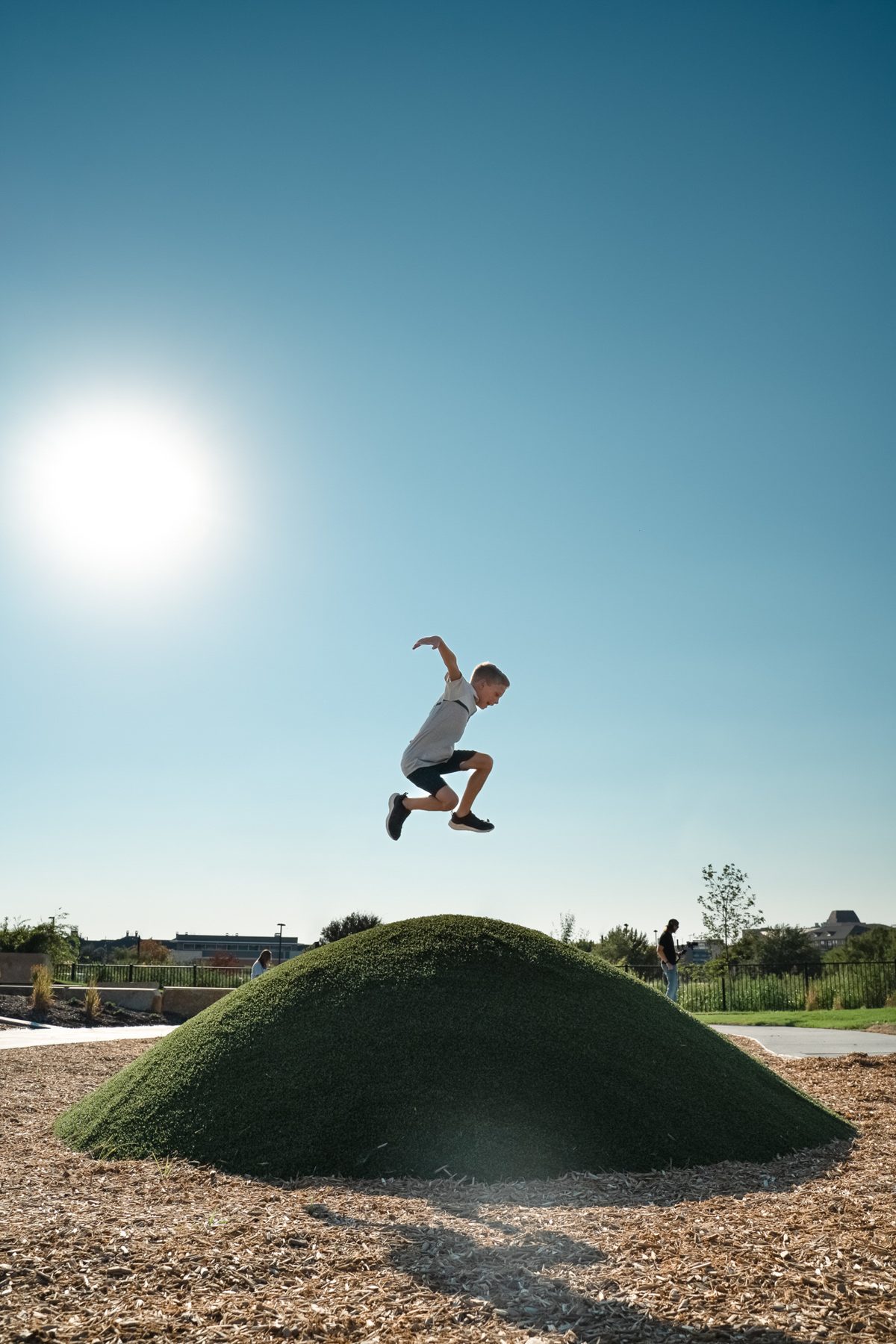 Boy jumping off a turf play mound in a Valley Quest park