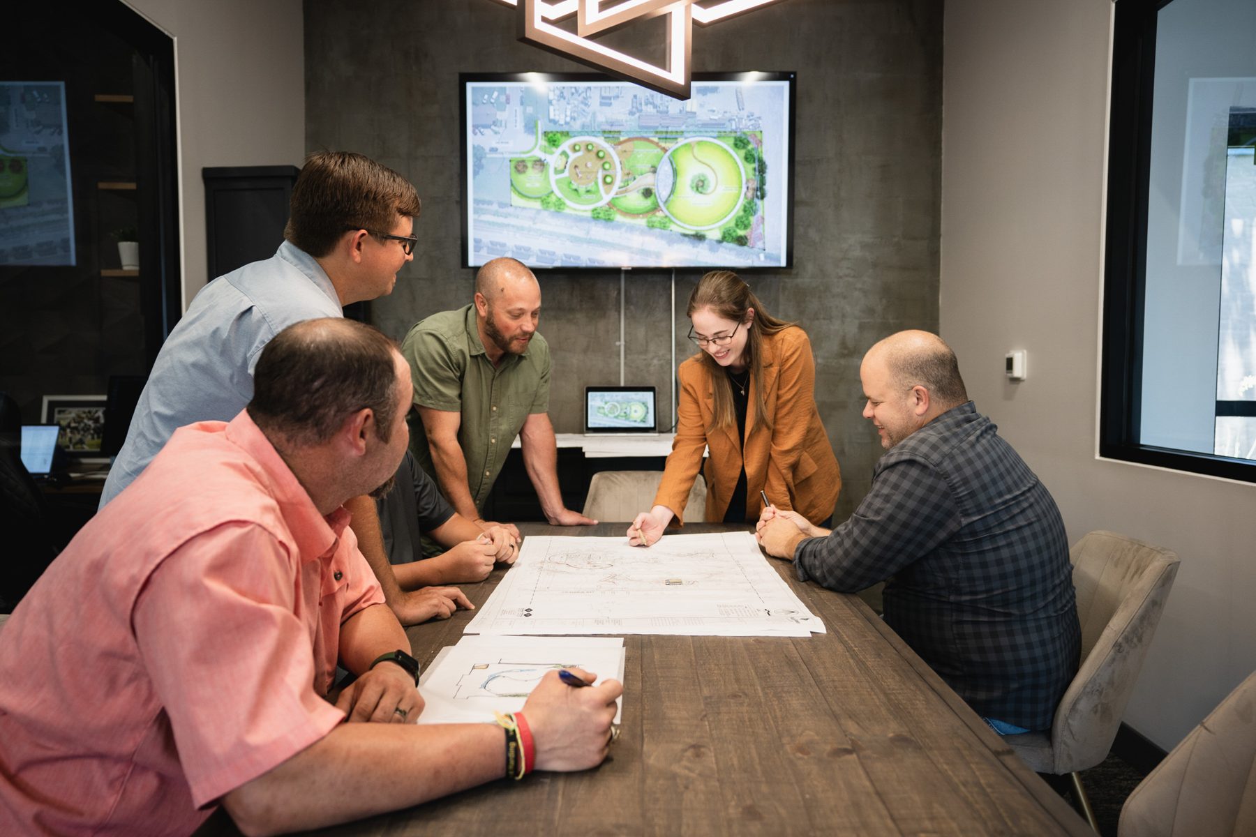 Valley Quest designers reviewing a printed park plan under the rendering on screen