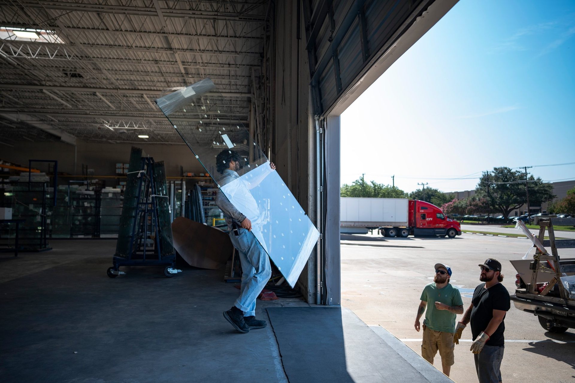Worker carrying a sheet of glass across the loading dock